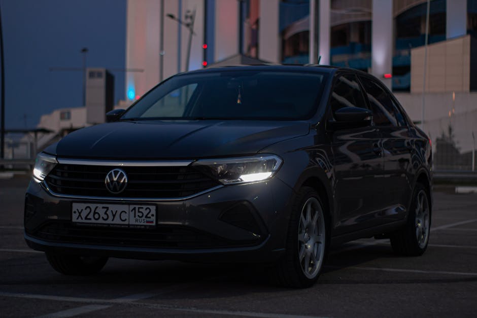 Volkswagen Polo headlamps illuminated in a city parking lot during dusk.