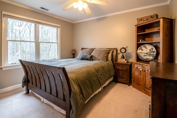 Warm and cozy bedroom interior featuring a wooden bed frame and furniture, with a large window view.
