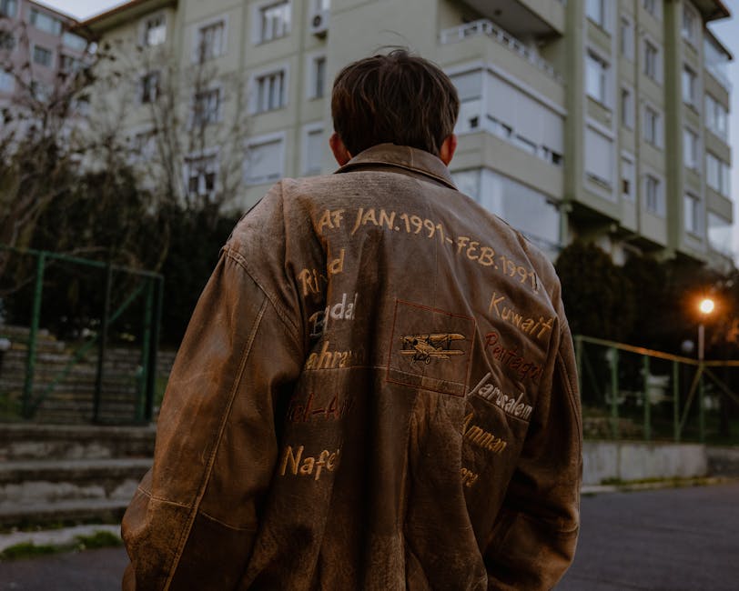 Back view of a man wearing a brown embroidered leather jacket standing in an urban setting.
